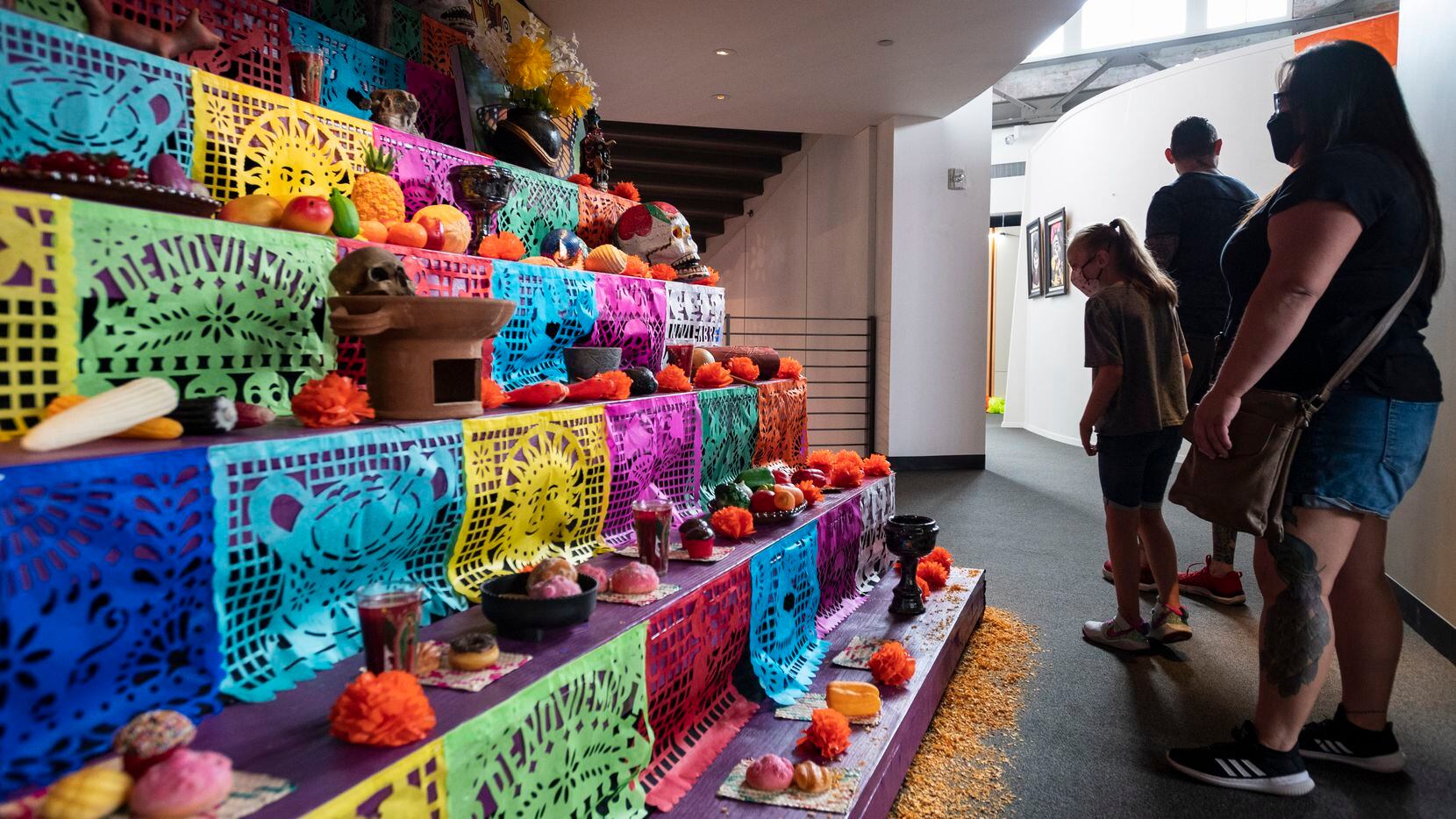 Personas visitan un altar del Día de Muertos en la exhibición Mundo Latino dentro de la...