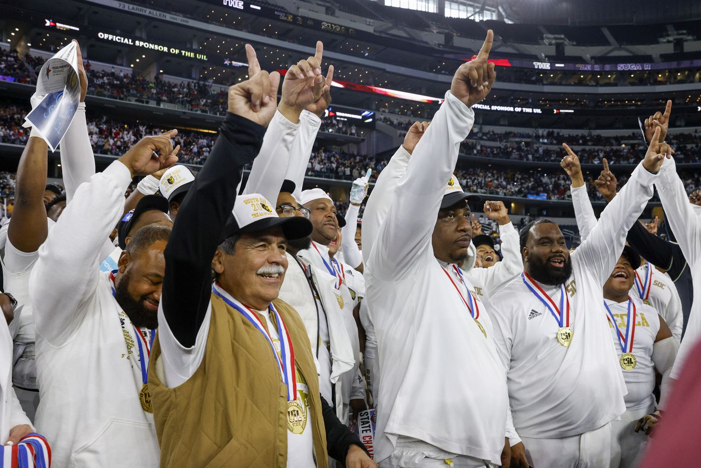 Dallas ISD Superintendent Michael Hinojosa (left) and South Oak Cliff head coach Jason Todd (center) celebrate with the team after winning the Class 5A Division II state championship game at AT&T Stadium in Arlington, Saturday, Dec. 18, 2021. South Oak Cliff defeated Liberty Hill 23-14 for Dallas ISD’s first title since 1958. (Elias Valverde II/The Dallas Morning News)