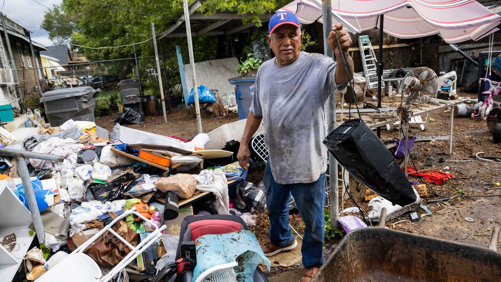 Juan Garcia cleans out the items from his home damaged by the Monday morning floods on...