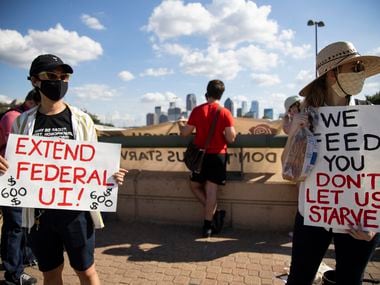 Linh Bui (left) and Ivy Vance (right) hold signs asking for the extension of federal employment benefits over North Central Expressway on July 24, 2020 in Dallas.