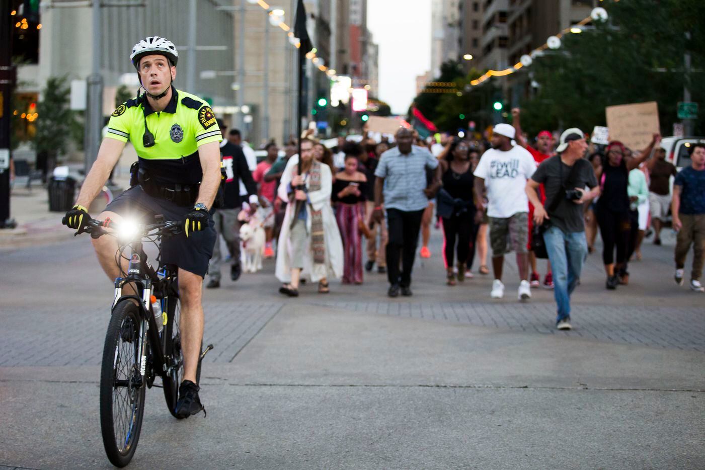 A Dallas Police officer looks up as he rides a bicycle through the intersection of Main and...