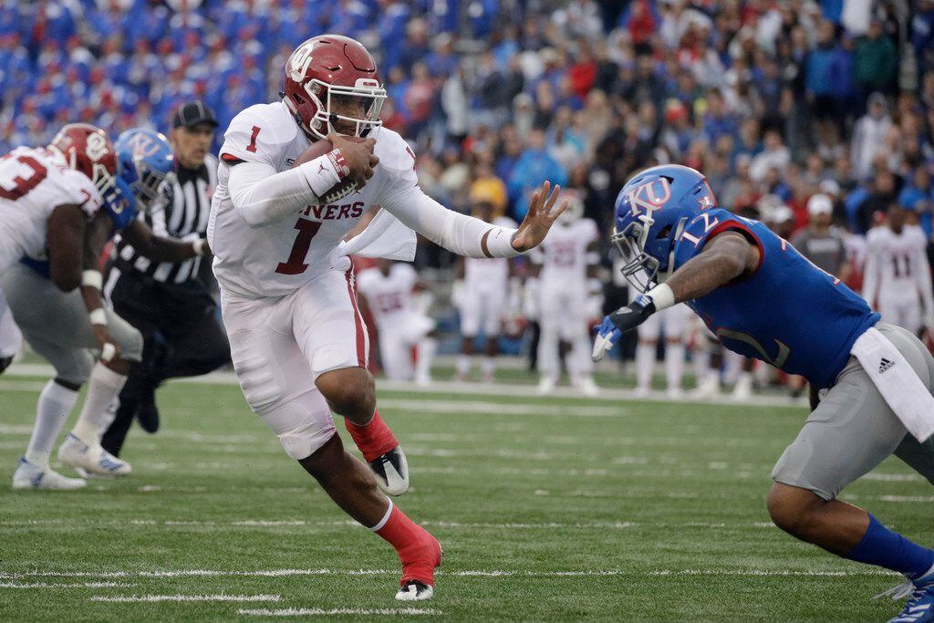 Oklahoma quarterback Jalen Hurts (1) gets past Kansas safety Jeremiah McCullough (12) as he runs the ball during the first half of an NCAA college football game Saturday, Oct. 5, 2019, in Lawrence, Kan. (AP Photo/Charlie Riedel)