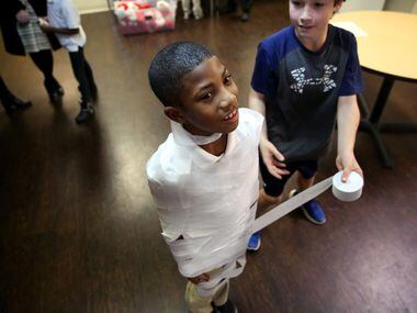 Jeremiah London, 8, (left0 gets wrapped in crepe paper by volunteer John Charest, 11, during...