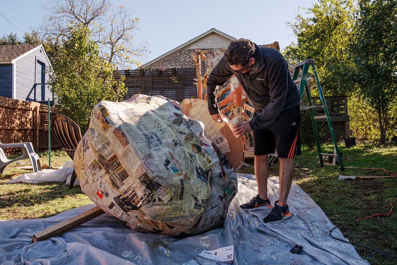Artist Giovanni Valderas adds glue to a giant calavera, or human skull sculpture, in his back yard in Dallas on Friday.