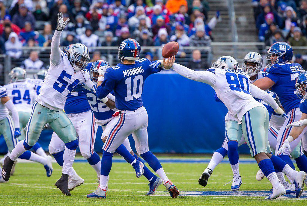 Dallas Cowboys defensive end Demarcus Lawrence (90) knocks the ball away from New York Giants quarterback Eli Manning (10) as Dallas Cowboys middle linebacker Jaylon Smith (54) applies pressure during the first half of an NFL football game at MetLife Stadium on Sunday, Dec. 30, 2018, in East Rutherford, New Jersey.  The fumbled ball floated high in the air before being caught by Cowboys defensive tackle Antwaun Woods. Lawrence was credited with a sack on the play.  (Smiley N. Pool/The Dallas Morning News)