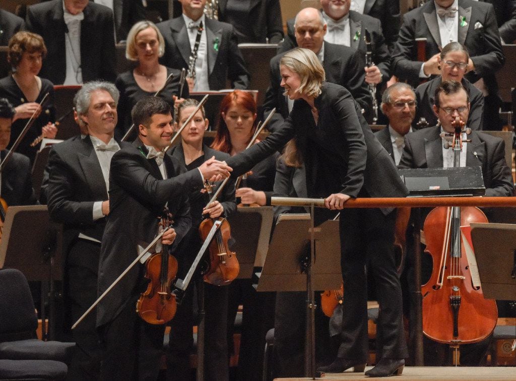 Conductor Ruth Reinhardt shakes hands with Concertmaster Nathan Olson after Lutoslawski's...