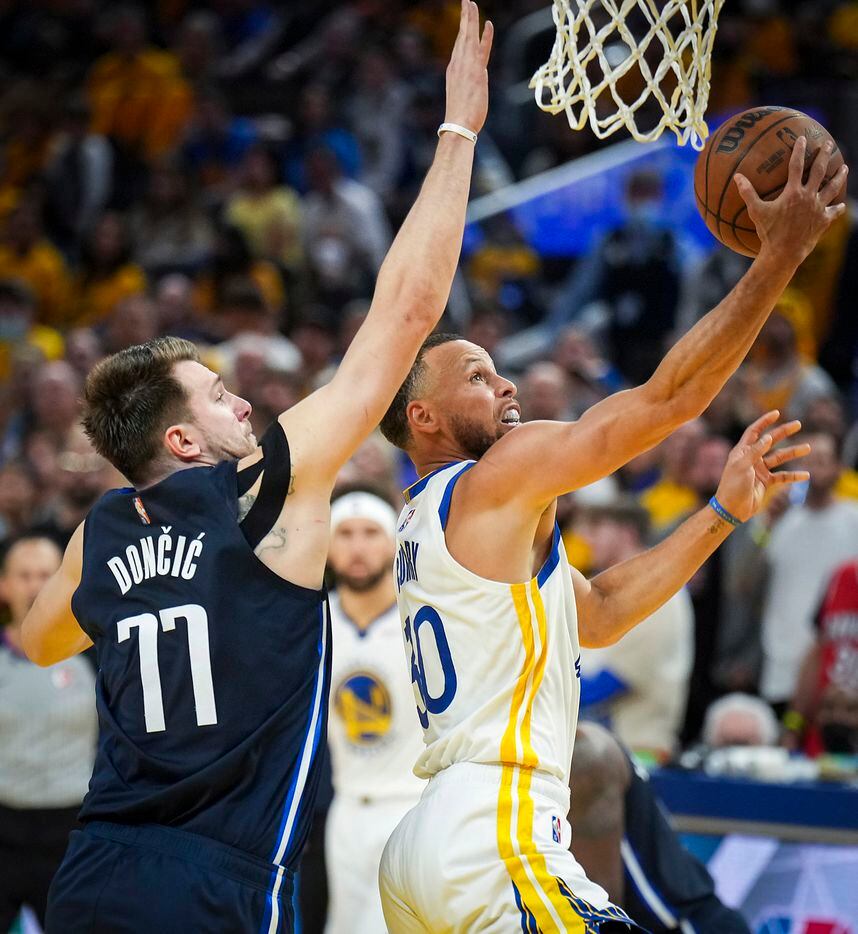 Golden State Warriors guard Stephen Curry (30) scores past Dallas Mavericks guard Luka...