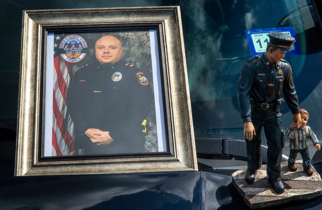 A photograph of A.J. Castaneda and a statue adorn the hood of a police vehicle at the Grand...