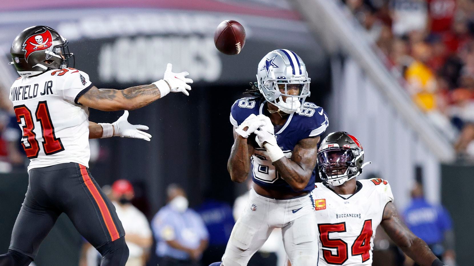 Dallas Cowboys wide receiver CeeDee Lamb (88) lets a pass slip through his fingers in the third quarter allowing Tampa Bay Buccaneers cornerback Carlton Davis (not pictured) to intercept it at Raymond James Stadium in Tampa, Florida, Thursday, September 9, 2021. Joining in on the play is Tampa Bay Buccaneers safety Antoine Winfield Jr. (31). The Cowboys faced the Tampa Bay Buccaneers in the NFL season opener.