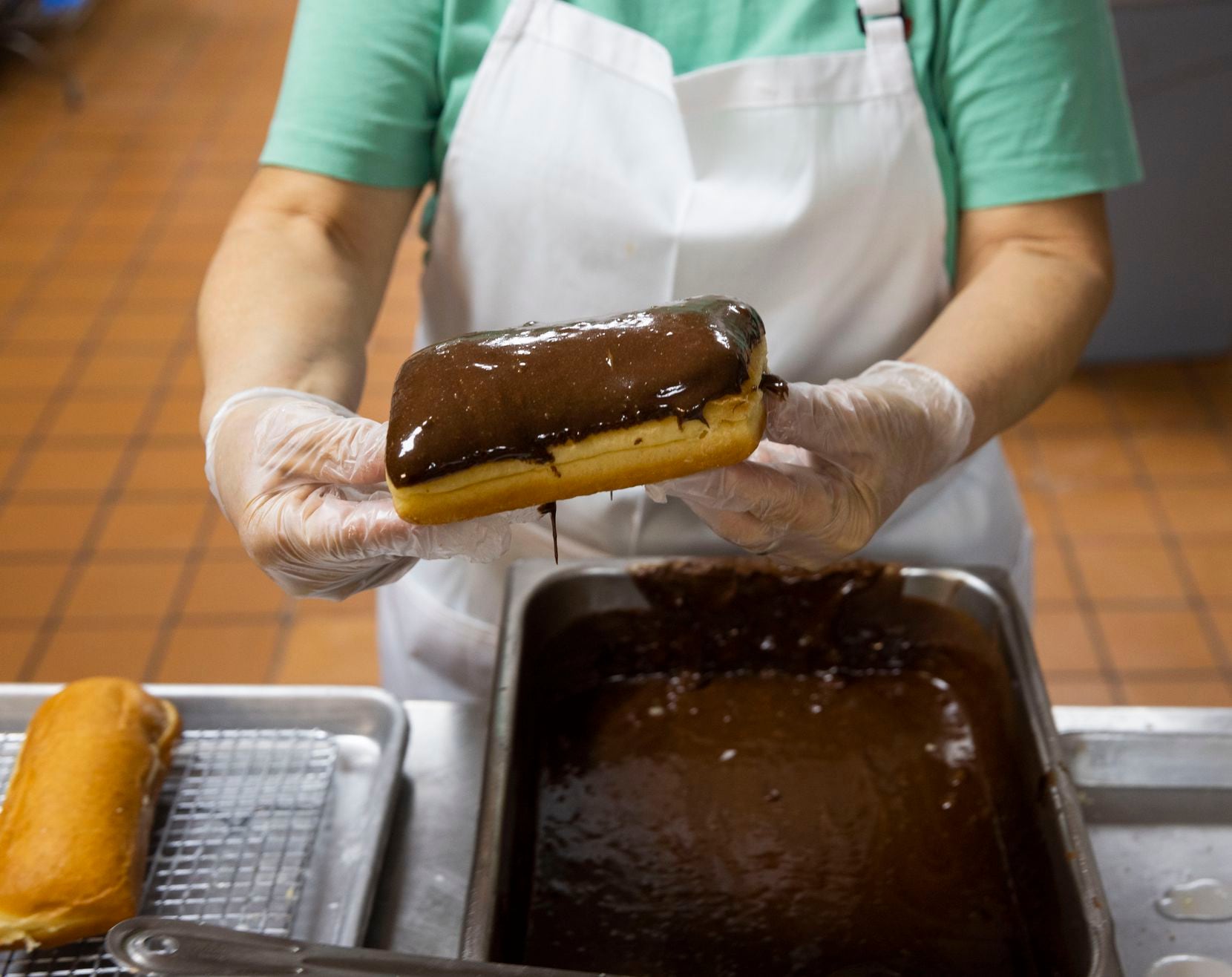 Maria Mendoza, who has been working at Lone Star Donuts for over 30 years, glazes a...