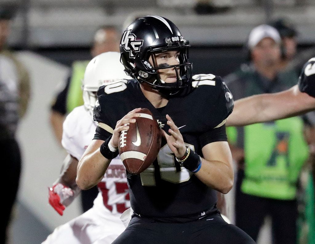 Central Florida quarterback McKenzie Milton, right, looks for a receiver as he is pressured...