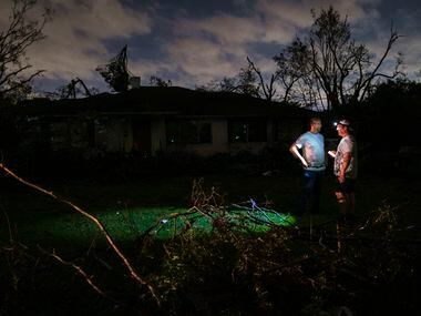 Residents survey tornado damage to their darkened neighborhood near the intersection of...