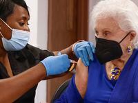 Registered nurse Barbara Davis, left, administers a flu shot on Dallas County Judge Clay...