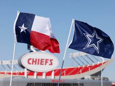 A Texas flag and Cowboys flag fly over tailgaters before an NFL football game between the...
