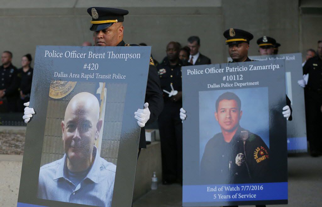 Honor guard carry portraits of fallen officers during a candlelight vigil at City Hall, Monday, July 11, 2016, in Dallas. Five police officers were killed and several injured during a shooting in downtown Dallas last Thursday night. (AP Photo/Tony Gutierrez)
