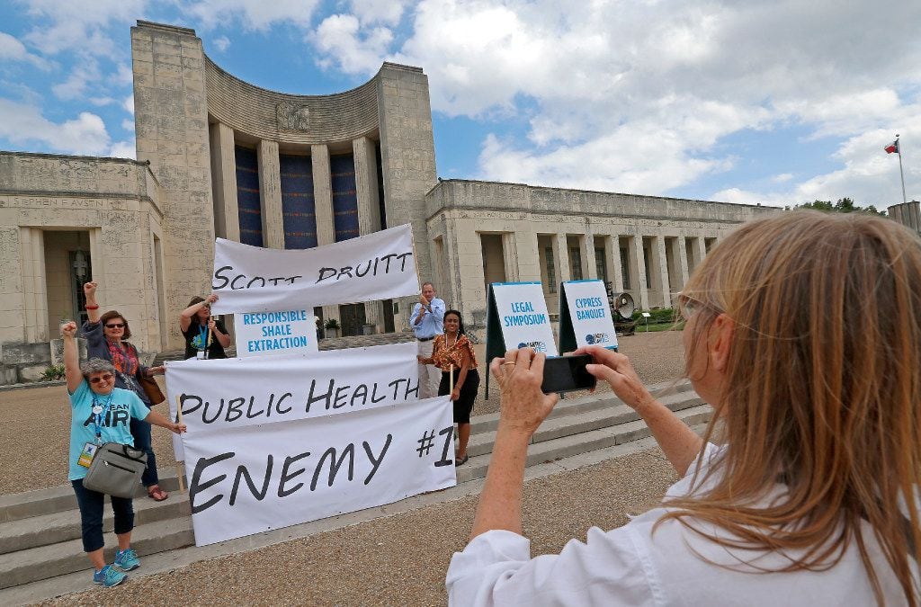 Valerie Walraven (right) takes a group photo of some of those protesting Pruitt's visit.
