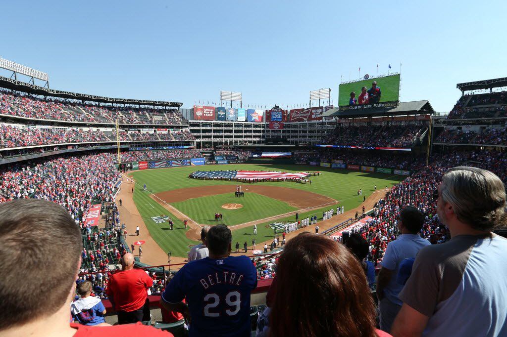 Fans sing along to the national anthem before the Texas Rangers and Toronto Blue Jays play...