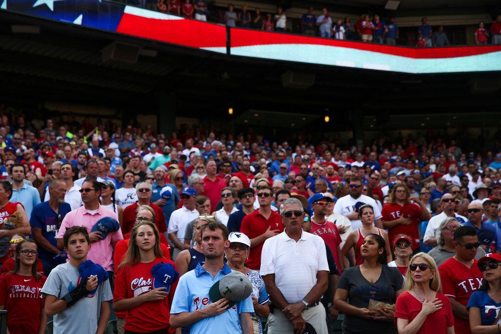 Fans stand and sing along to âGod Bless Americaâ during a MLB game between Texas Rangers...