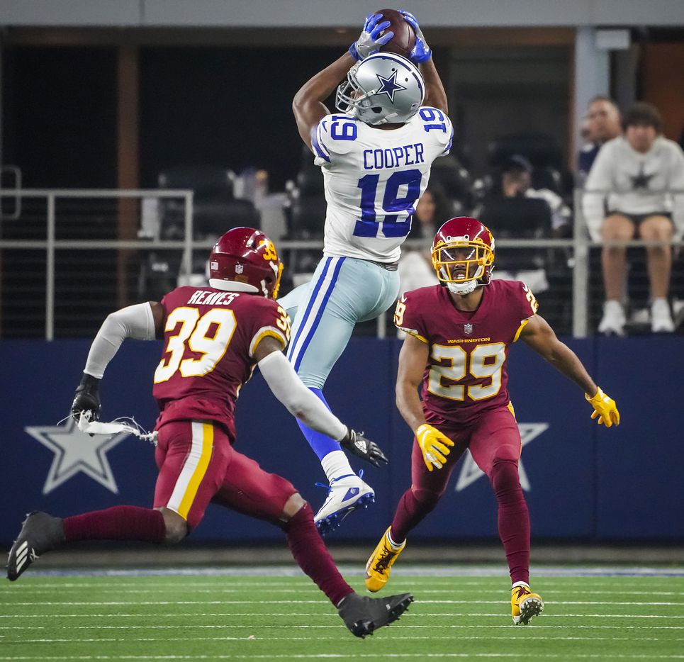 Dallas Cowboys wide receiver Amari Cooper (19) catches a pass as Washington Football Team defensive back Jeremy Reaves (39) and cornerback Kendall Fuller (29) defend during the first half of an NFL football game at AT&T Stadium on Sunday, Dec. 26, 2021, in Arlington.