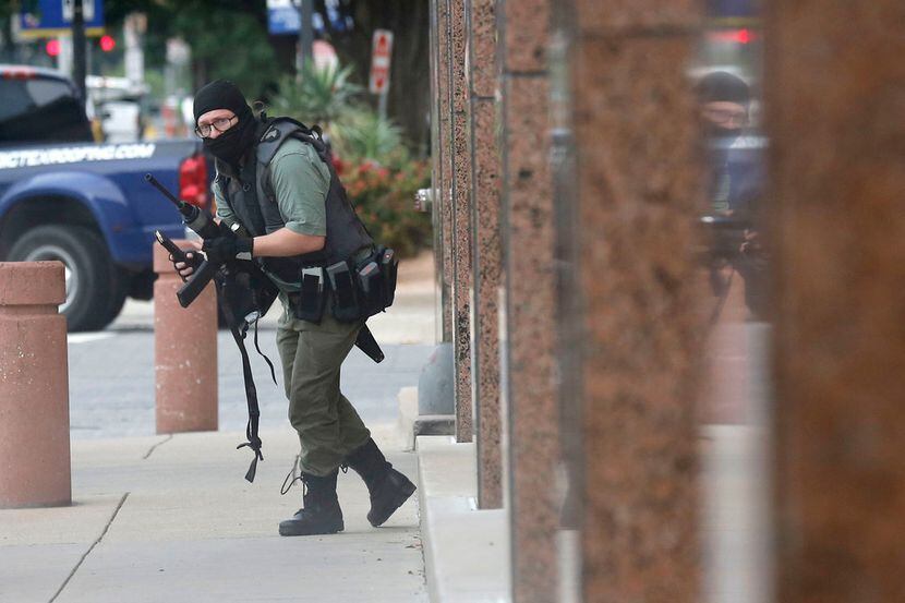 An armed shooter outside the Earle Cabell Federal Building looks in the direction of Dallas...