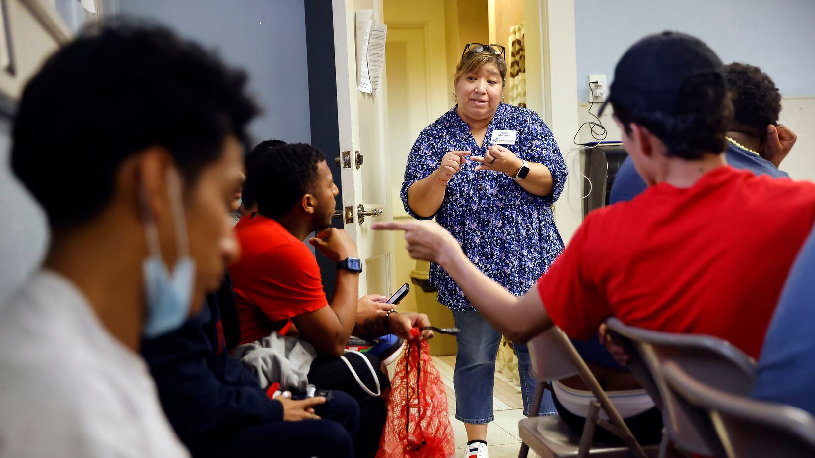 Associate Pastor Isabel Márquez  (center) visits with young migrants to arrange their travel...