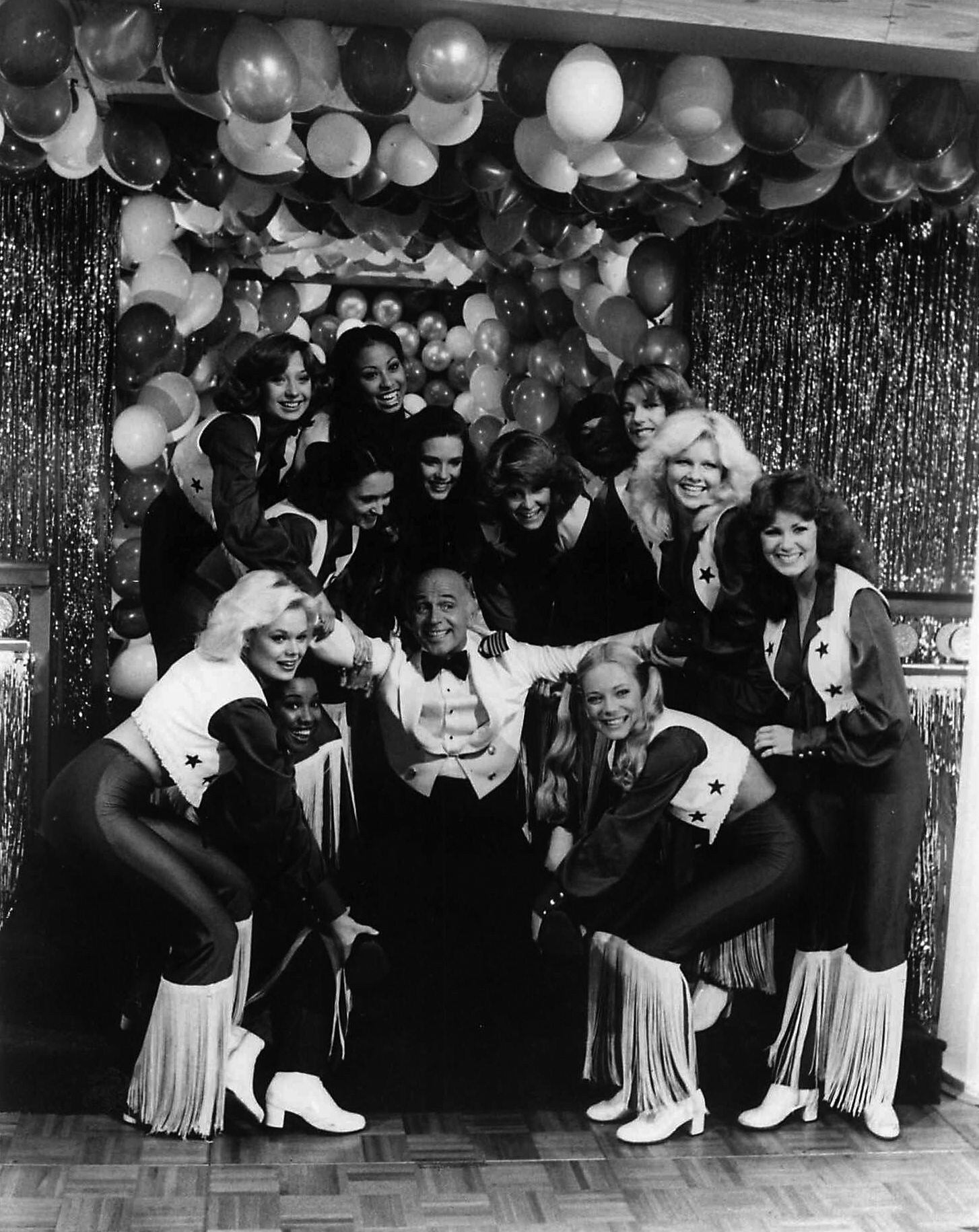 In the late 1970s, the Dallas Cowboys Cheerleaders were guest stars on ABC's hit TV show, 'The Love Boat.' At center in the photo is actor Gavin MacLeod.