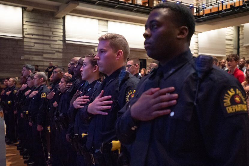 Dallas police officers stand for the Pledge of Allegiance at the start of a graduation...