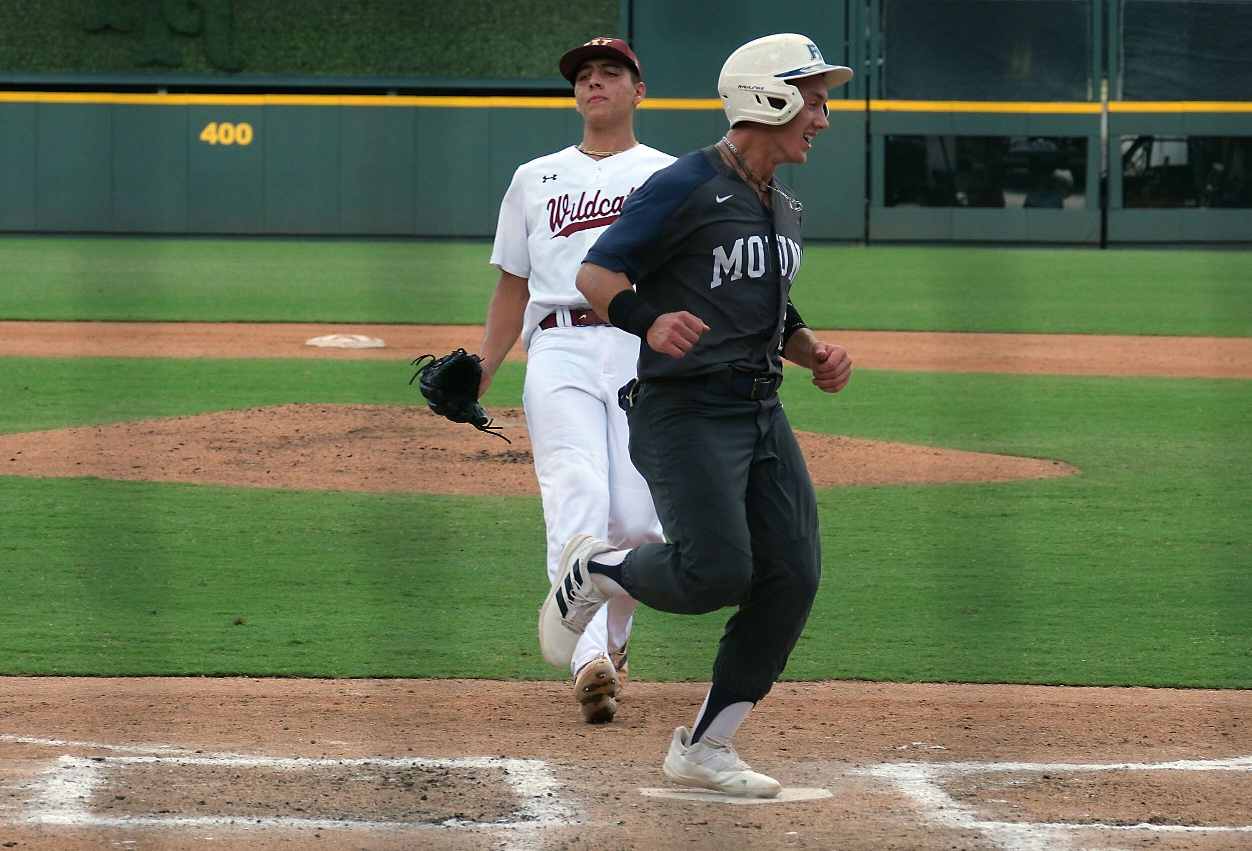 Flower Mound Sam Erickson, (21), crosses home plate as Cypress Woods pitcher tries to cover...