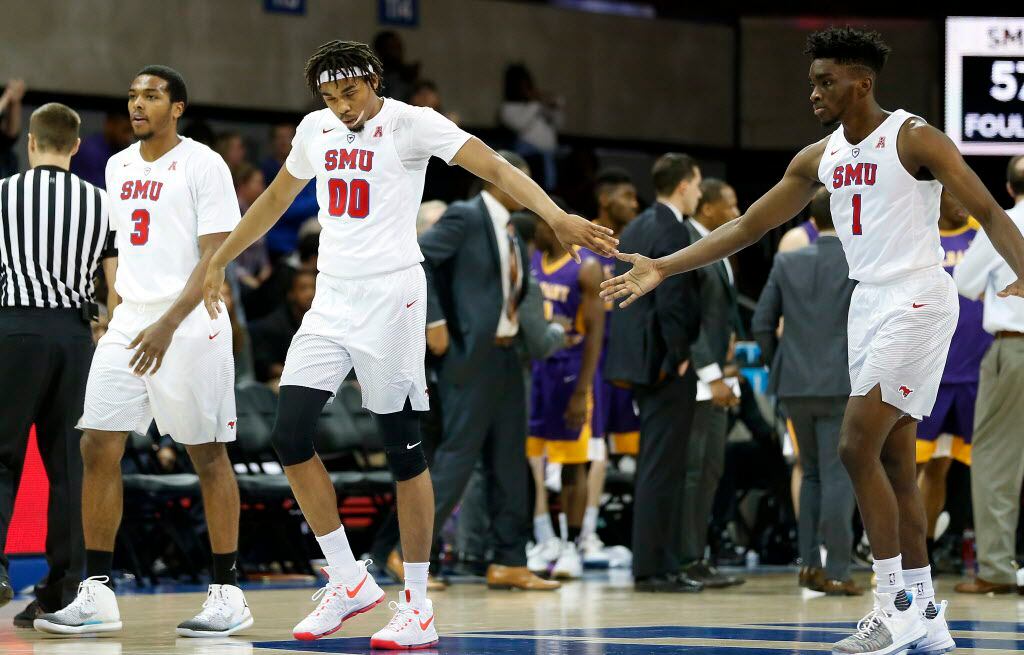 SMU guard Shake Milton (1) and forward Ben Moore (00) touch hands as they walk to the bench...