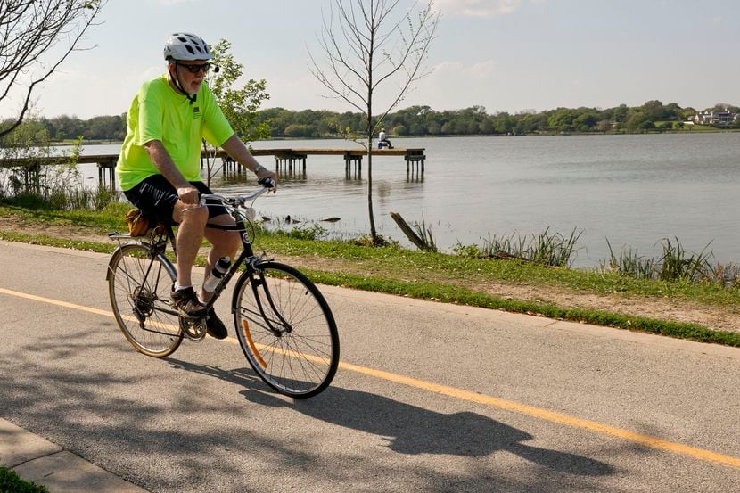 A cyclist rides along the White Rock Lake Trail at White Rock Lake on Monday, April 3, 2023...