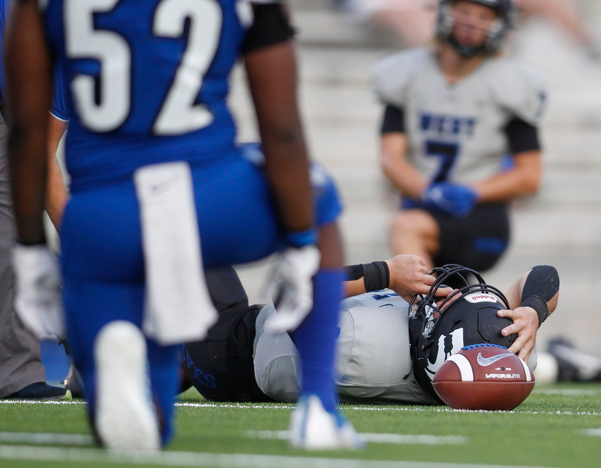 Plano West quarterback Vance Feuerbacher (19) receives medical attention during an injury...
