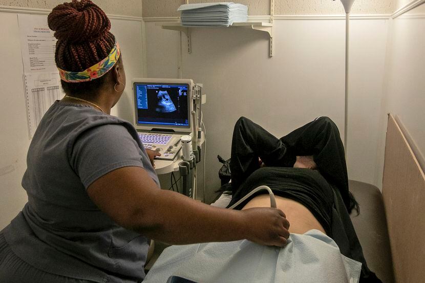 two pregnant women looking ultrasound photo album in living room Stock  Photo