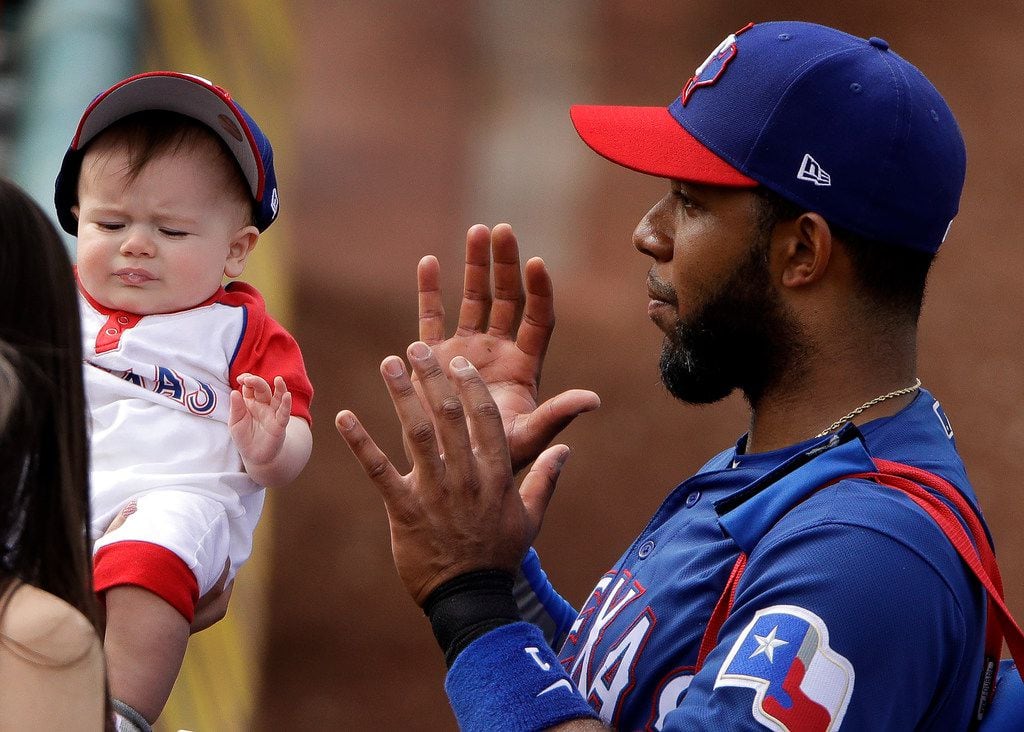 Texas Rangers' Elvis Andrus poses with a baby as he leaves field after the fifth inning of a spring training baseball game against the Chicago White Sox Friday, March 1, 2019, in Surprise, Ariz. (AP Photo/Charlie Riedel)