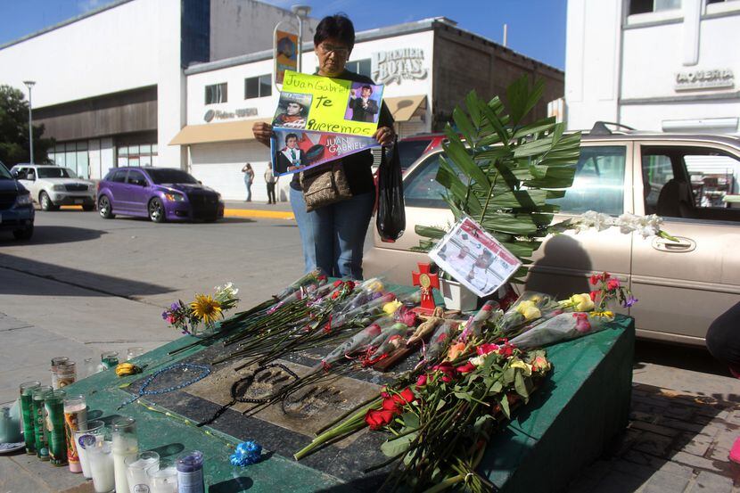 Una mujer sostiene un cartelón con un mensaje de aprecio al cantante Juan Gabriel en Ciudad...