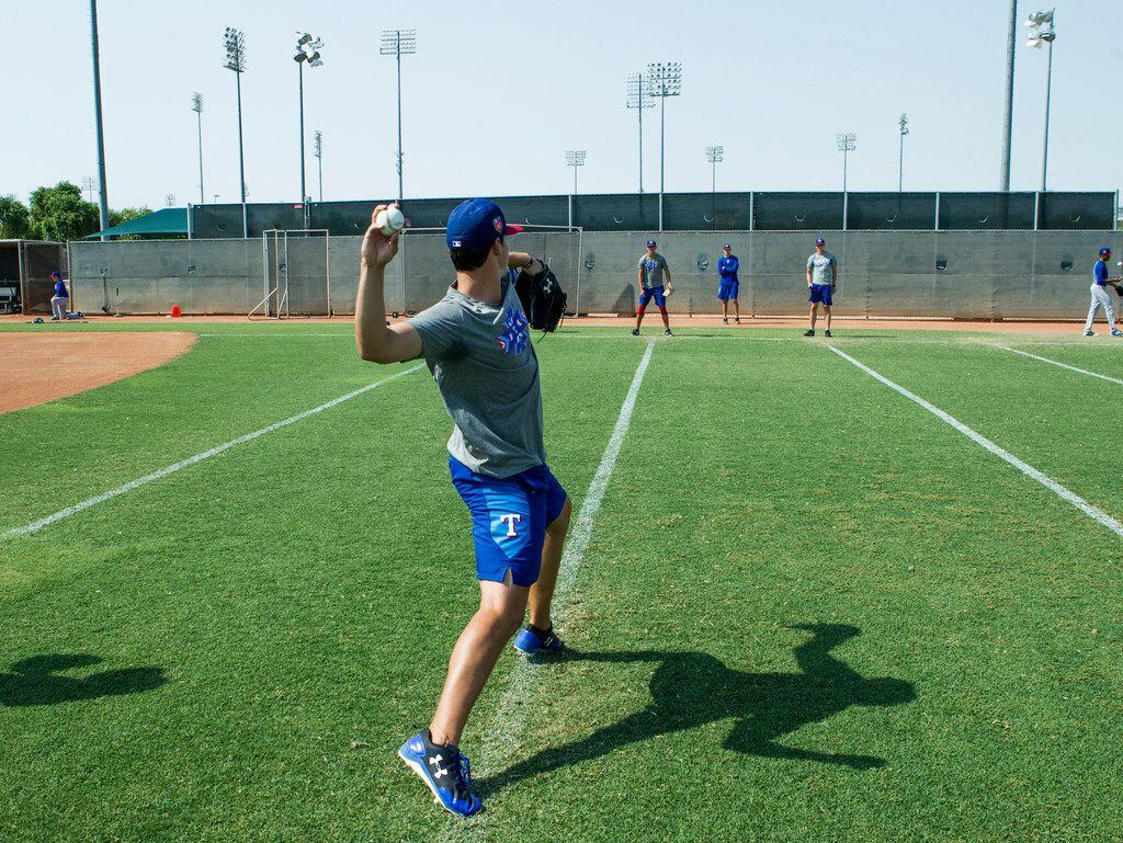 Texas Rangers' pitcher Cole Winn works on his delivery while doing a little long toss with...
