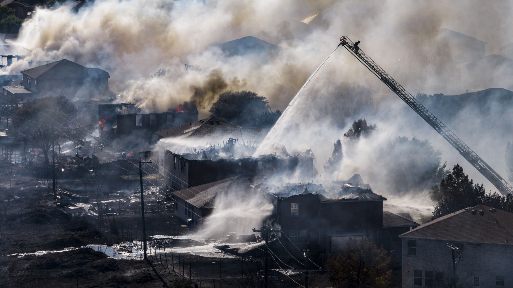 Fire fighters battle a grass fire that destroyed several homes in the 14000 block of...