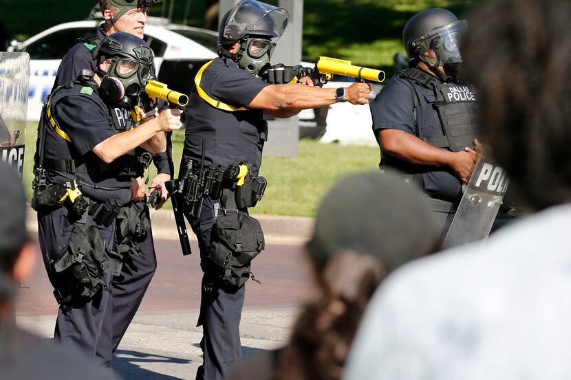 Agentes de la Policía de Dallas posicionados para disparar contenedores de gas lacrimógeno...