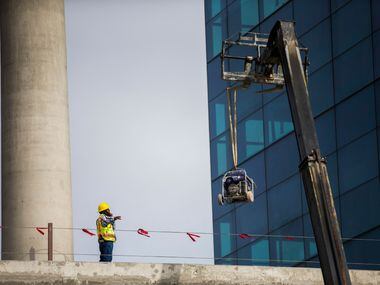 A construction worker guides a forklift holding equipment to the second level of the front...