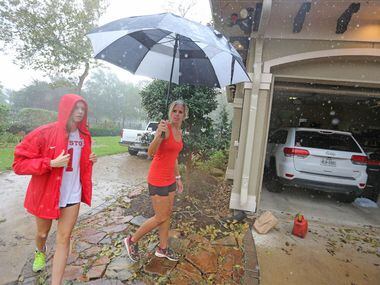 Abby Odneal, left, and her mother Ashley dodge raindrops to view the damage to their Sienna...