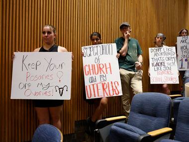 Abortion rights supporters hold signs during a Denton City Council meeting at Denton City...