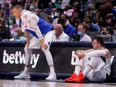 Dallas Mavericks center Kristaps Porzingis (left) and guard Luka Doncic wait to go back in the game against the Utah Jazz in a preseason game at the American Airlines Center in Dallas, Wednesday, October 6, 2021.