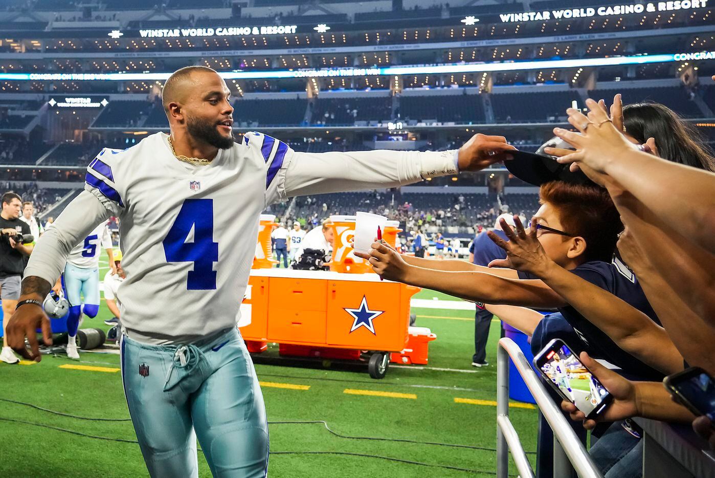 Dallas Cowboys quarterback Dak Prescott (4) gives his hat to a young fan as he leaves the...