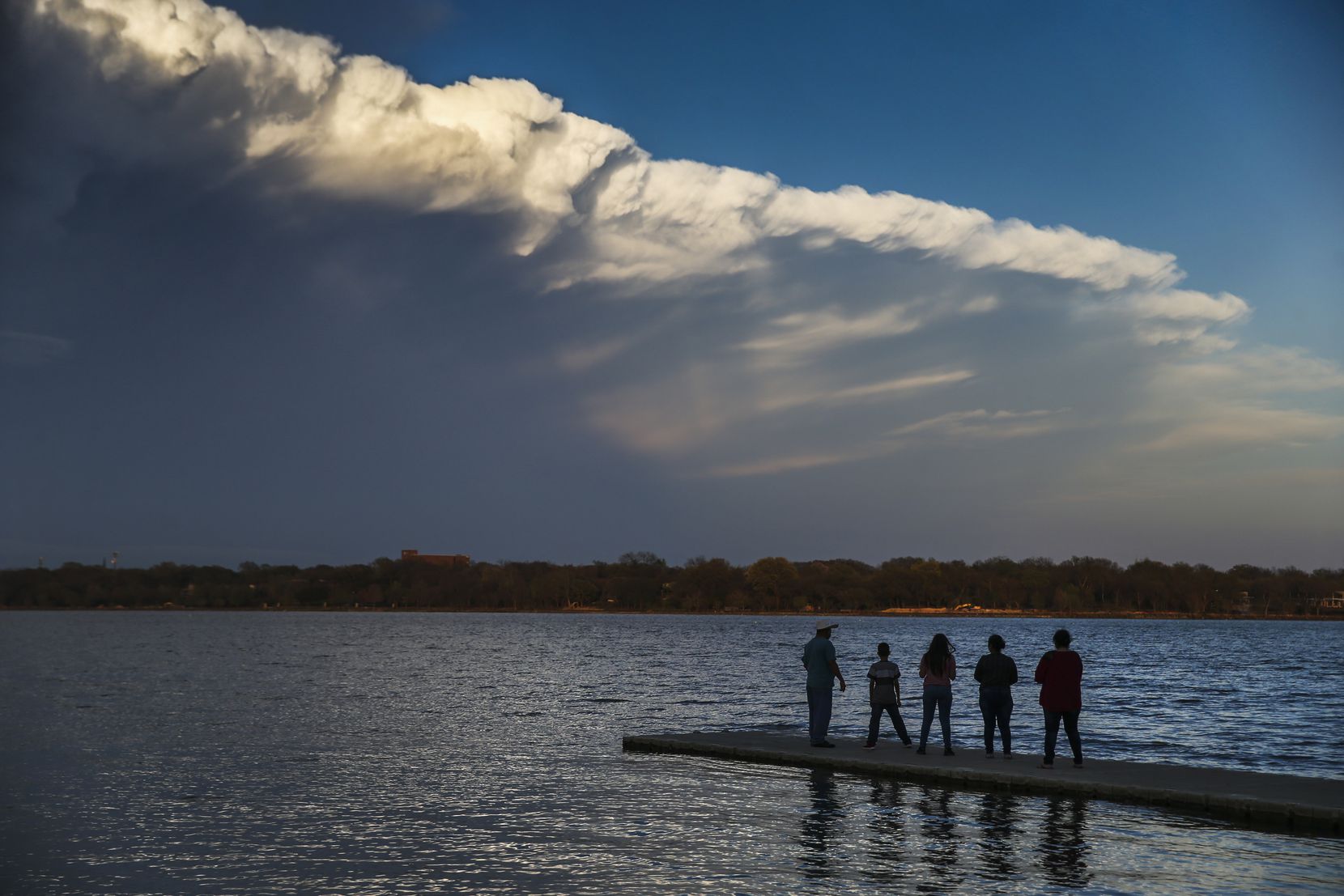 People watch passing clouds from a dock at White Rock Lake on Sunday afternoon, March 24,...