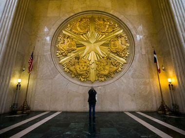 A man takes a photo of the large gold seal inside the historic Hall of State building on...