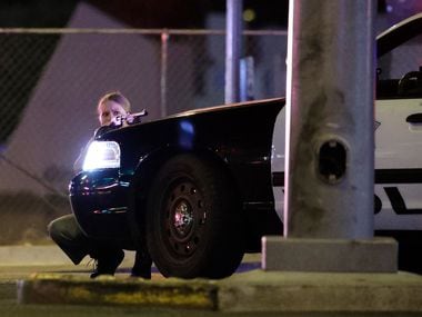 A police officer takes cover behind a squad car during a shooting near the Mandalay Bay...