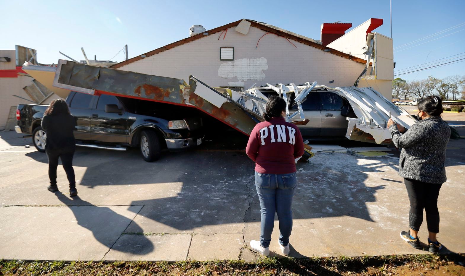 Burger Box restaurant employees (from left) Ana Espinoza, Jennifer Capado, and Maria Espinoza inspect the damage where two customers vehicles were trapped under the drive thru roof awning, Wednesday, November 24, 2020. A tornado-warned storm tore the roof off, trapping the drivers in their vehicles on S. Cooper St.