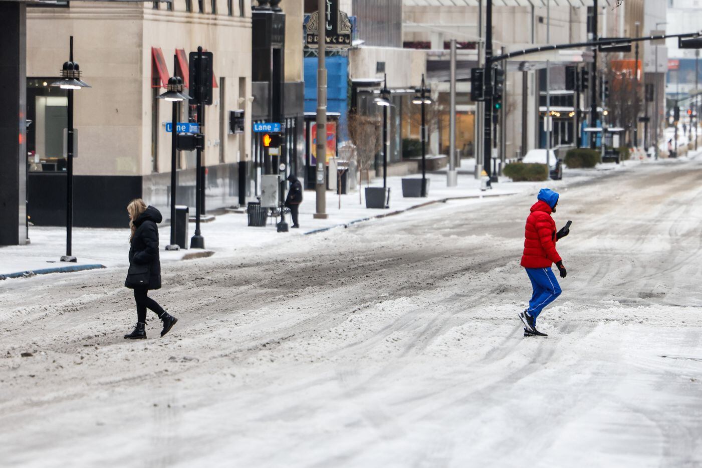 Pedestrians cross Commerce St in downtown Dallas covered by sleet on Tuesday, Jan. 31, 2023....