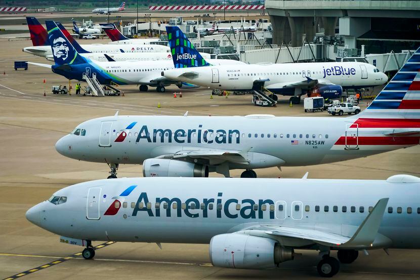 Un par de aviones de American Airlines esperan frente a las puertas en la terminal C del...