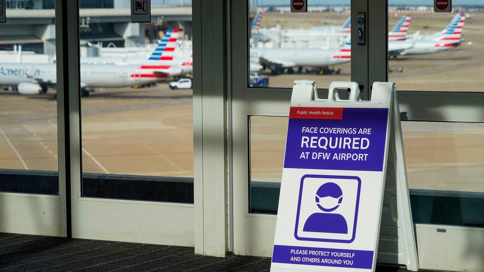 Signs at a Skylink train station notified travelers of face mask requirements as American Airlines planes were parked at Terminal C on Christmas Day at DFW Airport.