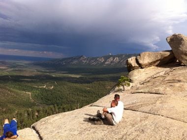 Tim Barber (center) sits next to his dad, Greg "Spanky" Barber, on a cliff at Philmont Scout...
